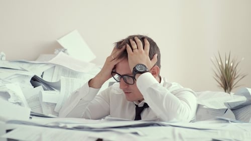 Stressed Businessman Overwhelmed by Paperwork in Office