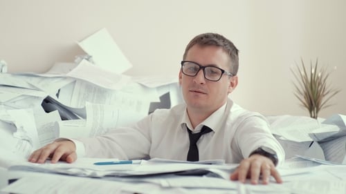 Stressed Businessman Surrounded by Paperwork in Office
