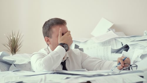 Stressed Man Overwhelmed by Paperwork in Office