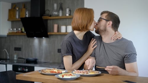 Husband and Wife Eat Breakfast Together. Behind the Wooden Bar, Behind the Modern Kitchen Interior