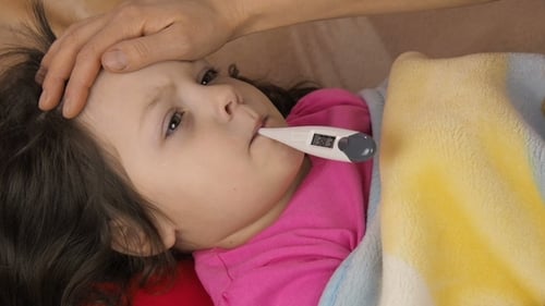 Sick Child Lying Down with a Thermometer