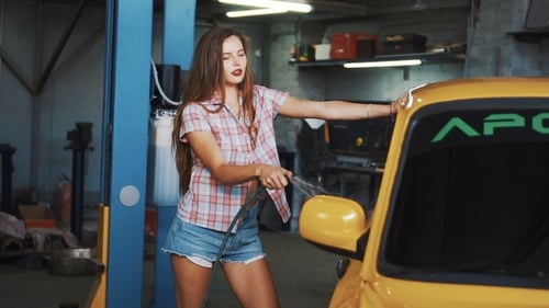 Attractive Woman Washing Yellow Car in Auto Shop