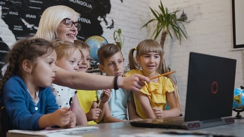 Children Learning with Teacher Using Laptop in Classroom