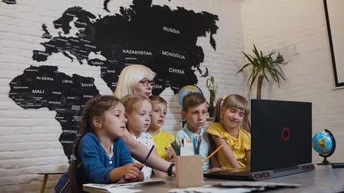 Young Woman Teacher Discussing a Computer Program with a Group of Pupils. Female Teacher Using
