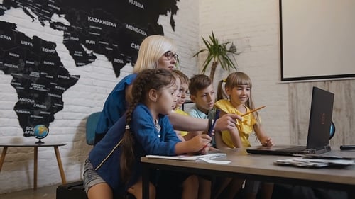 School Teacher and a Group of Elementary Students Working with a Laptop