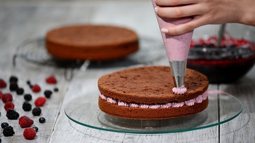 Woman Decorating Chocolate Layer Cake with Cream