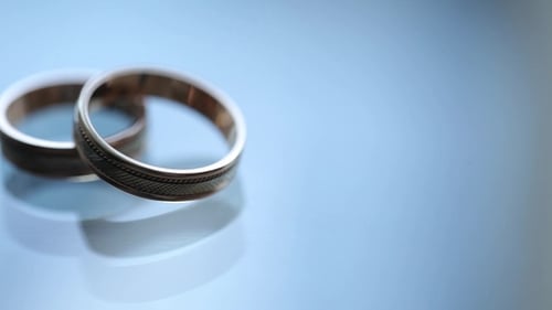 Two Gold Wedding Rings on Reflective Surface