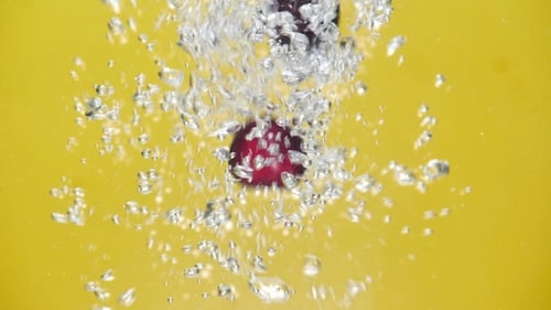 A Fresh Cherry Are Splashing Into Water on Yellow