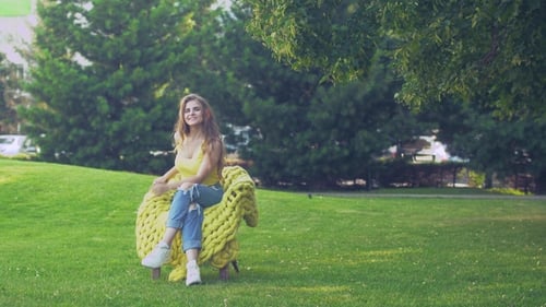 Belle fille assise dans le parc sur une chaise