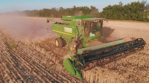 Aerial View of a Combine Harvester Working in a Field at Sunset