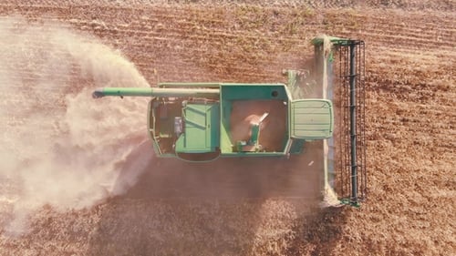 Aerial View of a Combine Harvester Working in a Field at sunset