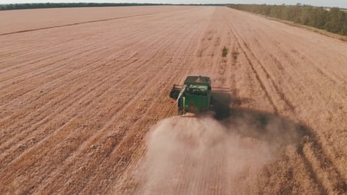 Aerial View of a Combine Harvester Working in a Field at Sunset