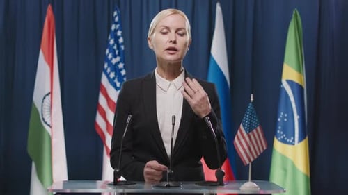 Woman Speaking at a Podium with Flags