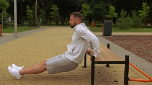 Man Doing Tricep Dips on Bench in Park