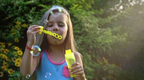 Girl Blowing Bubbles Outdoors on a Sunny Day
