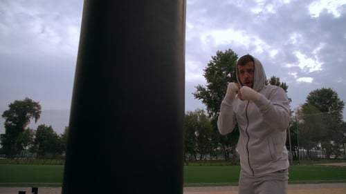 Man Wearing Hood Punches the Punchbag