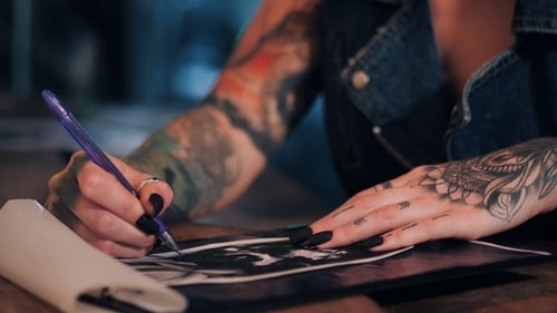 Close Up of Tattooed Artist Drawing
