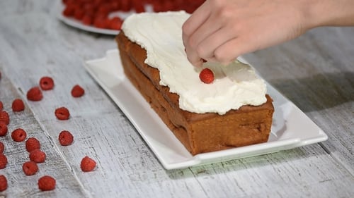 Decorating Cake with Fresh Raspberries and White Frosting