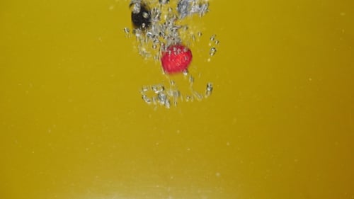 Many Fresh Berries Are Falling Into Water Against Yellow Background