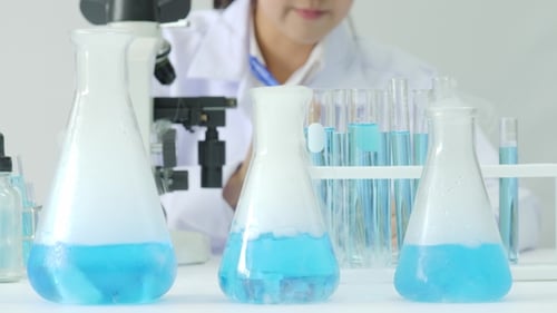 Woman Using Microscope in Laboratory for Research