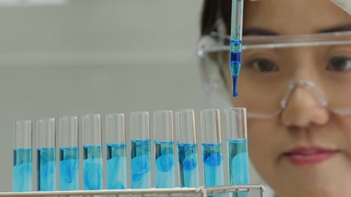 Scientist Carefully Adds Liquid to Test Tubes