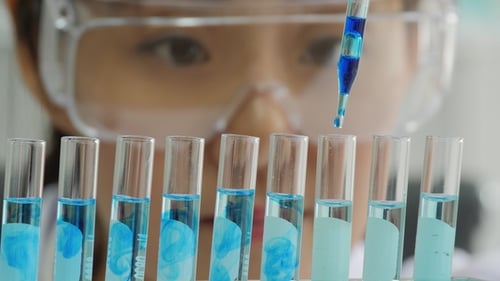 Blue Pipette Adding Fluid to Lab Test Tubes