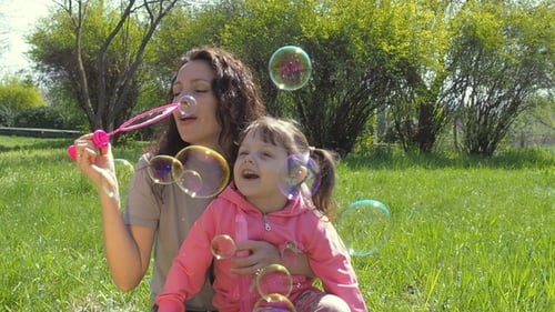 Mother and Child Enjoying Blowing Bubbles Outdoors