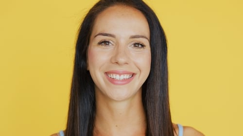 Smiling Woman Poses in Front of Yellow Background