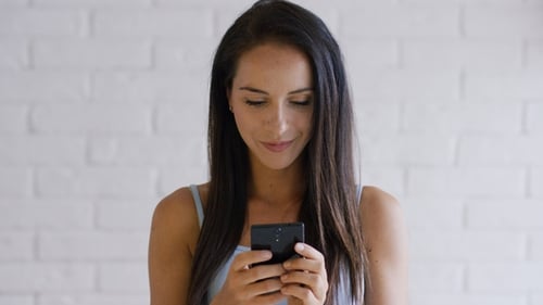 Smiling Woman Using Smartphone Device Indoors