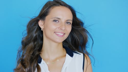 Smiling Woman with Windblown Hair Against Blue Background