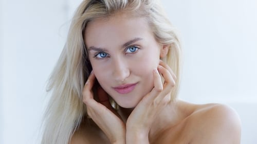 Woman Gently Touching Face in Bright Studio