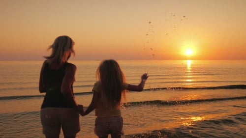 Mother and Child Run in Ocean at Sunset