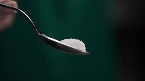 Sugar Crystals Falling from Silver Spoon