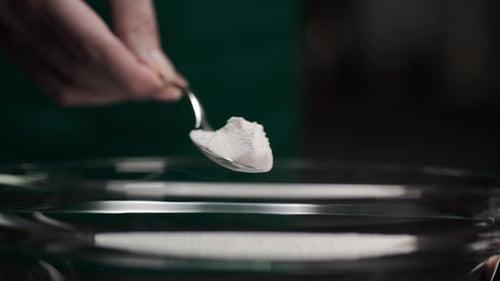 Der Küchenchef fügt der gekochten Mahlzeit Soda hinzu, Löffel und Mehl, Gewürze zur Mahlzeit, Kochen in der Küche