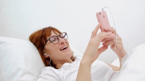 Patient Talking on Mobile Phone in Bed. Young Attractive Woman in Hospital Bed. Connected World and