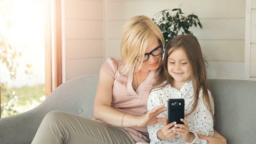 Mother and Daughter Use Smartphone on Couch