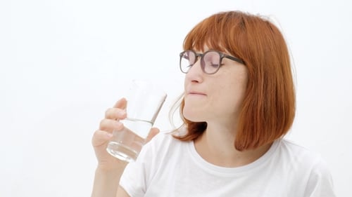 Woman With Glasses Drinks Water in Studio