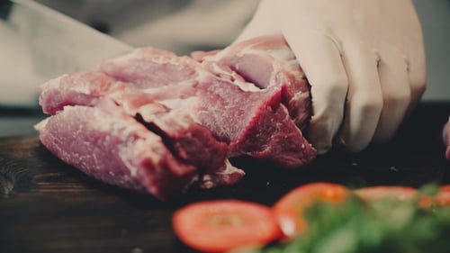 Chef Cutting Raw Meat on a Wooden Board