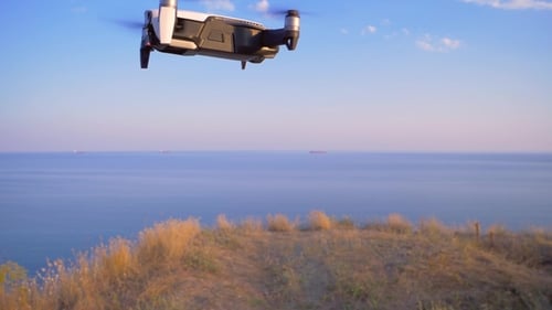 Quadrocopter Flies in Place Against the Background of the Sea UAV