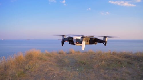 Quadrocopter Flies in Place Against the Background of the Sea UAV in