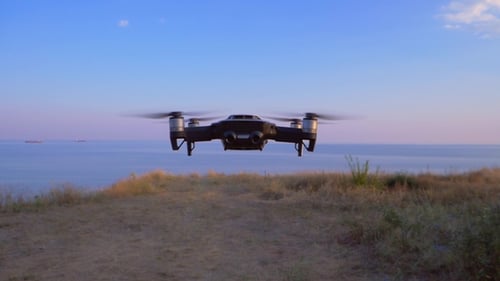 Quadrocopter Flies in Place Against the Background of the Sea UAV in