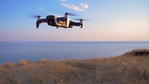 Quadrocopter fliegt vor dem Hintergrund des Meeres an Ort und Stelle