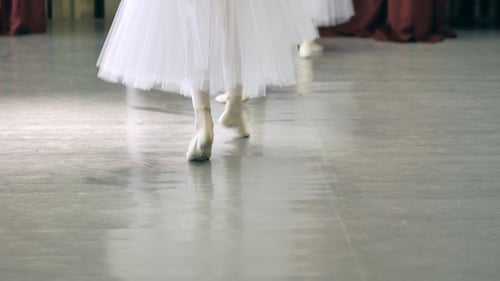 Ballet des jambes d'une fille dans des chaussures de ballet blanches pendant l'entraînement de ballet. Elément de danse classique