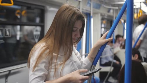 Junges Mädchen fährt in einem U-Bahn-Auto und nutzt das Internet in ihrem Smartphone