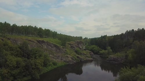 Drone View. Sniper Woman with a Sniper Rifle Sits on the Rocks on the River. Cameta Moving To Object