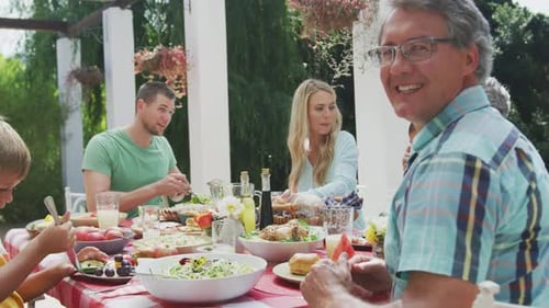 Family Shares Meal Outdoors Together Under Green Pergola