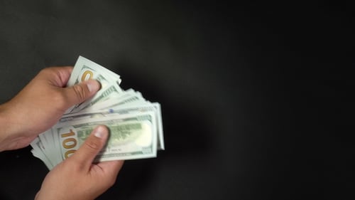 A Man Counts Money with His Hands on a Black Background