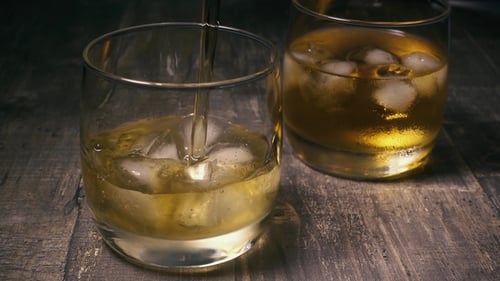 Golden Liquor Poured Over Ice in Glass