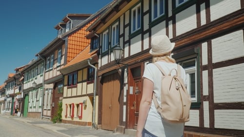A Woman in Summer Clothes with a Pink Backpack Strolls Along the Picturesque Street