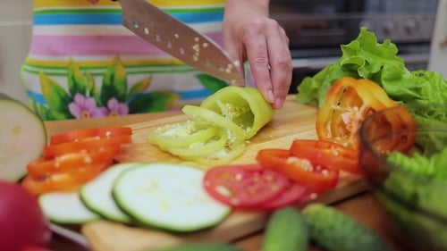 Woman Cuts Vegetables on a Wooden Cutting Board